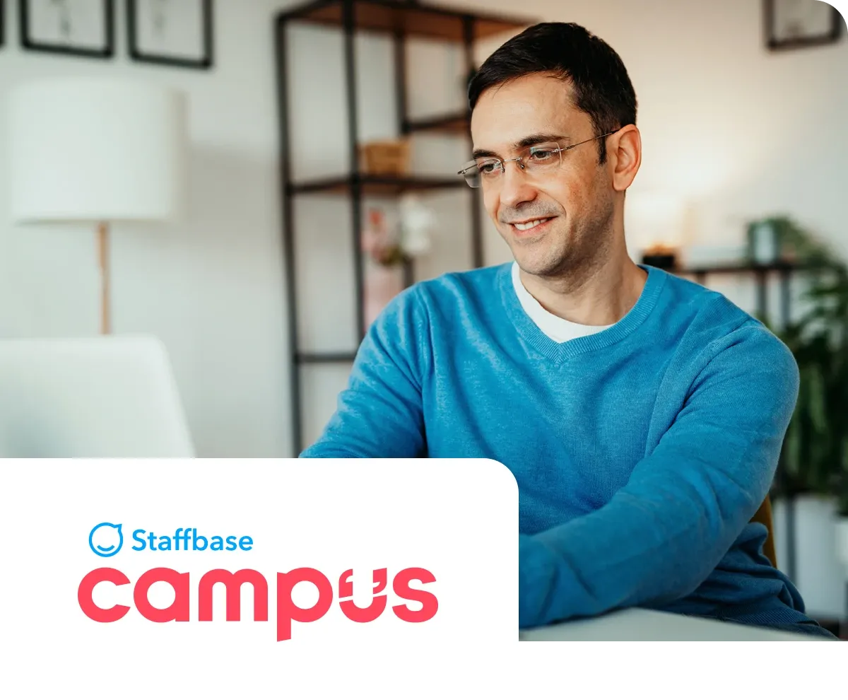 Man in a blue sweater working on a laptop at home, with "Staffbase Campus" logo in the foreground.